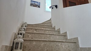 Uma escada com corrimão, paredes brancas e uma pequena janela com uma imagem.