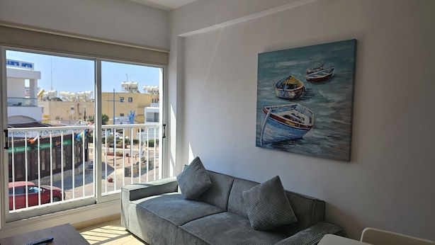 Un balcón con vistas a edificios y un cuadro de barcos en la pared.