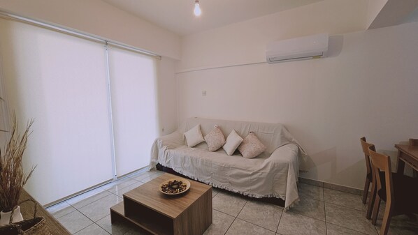 Una sala de estar con sofá, una mesa de centro y una mesa de comedor con sillas.