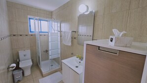 A bathroom with a glass-enclosed shower, a toilet, a sink with toiletries, and a mirror. - 140 VOR - Stay Chrisoula Beach Garden (Oroklini)