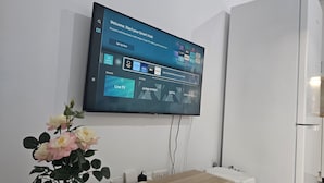 A flat-screen TV mounted on a wall displaying a smart hub interface with live TV options. - 145 NIC - Stay Historia Apartment (Nicosia)