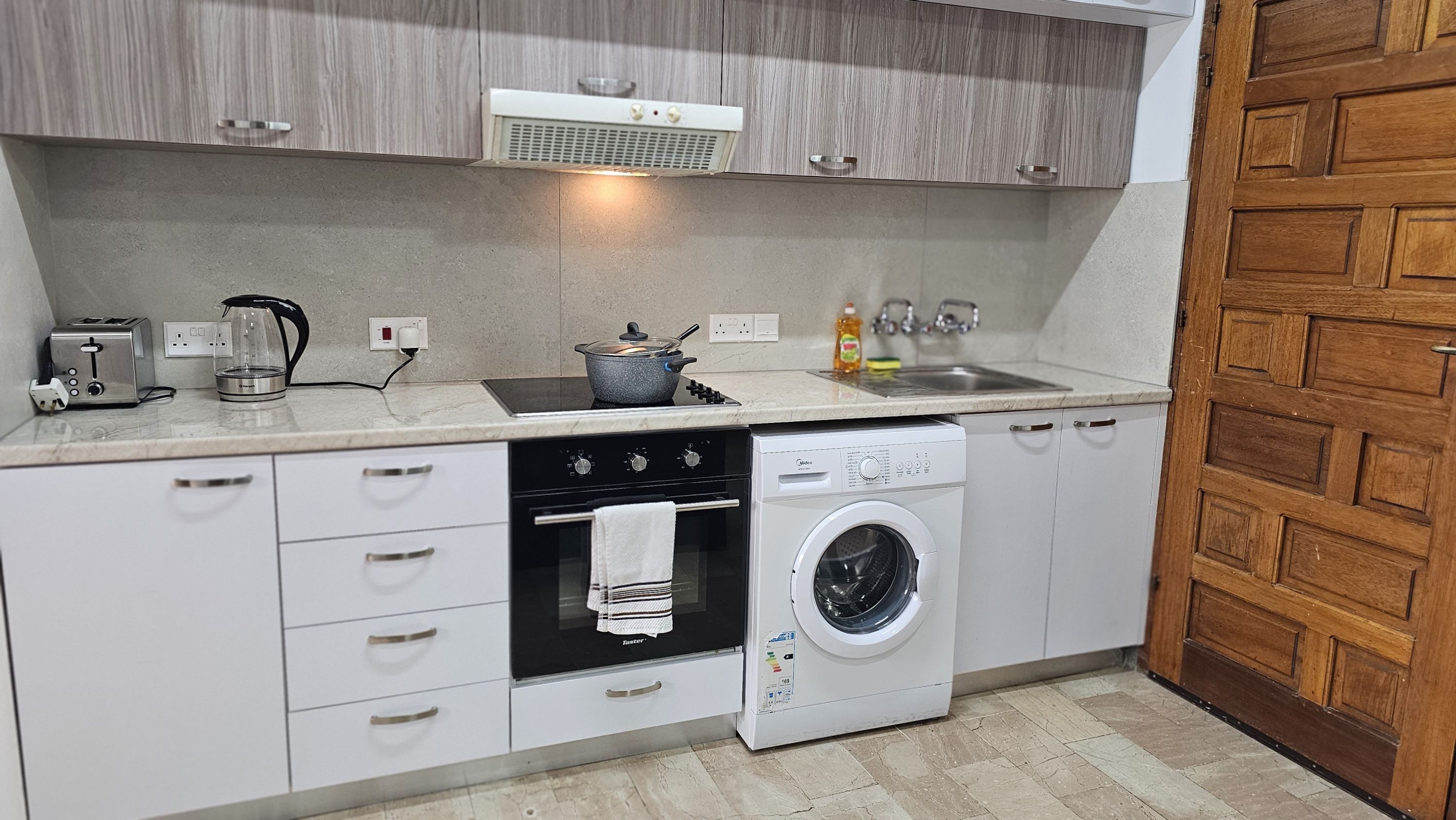A compact kitchen with a built-in oven, a dishwasher, a coffee maker, and a sink.