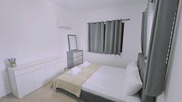 Un dormitorio con cama, cómoda, espejo y ventana con cortinas.