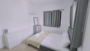 A bedroom with a bed, a dresser, a mirror, and a window with curtains. - 117 KPF - Stay Tranquil Haven (Paphos)