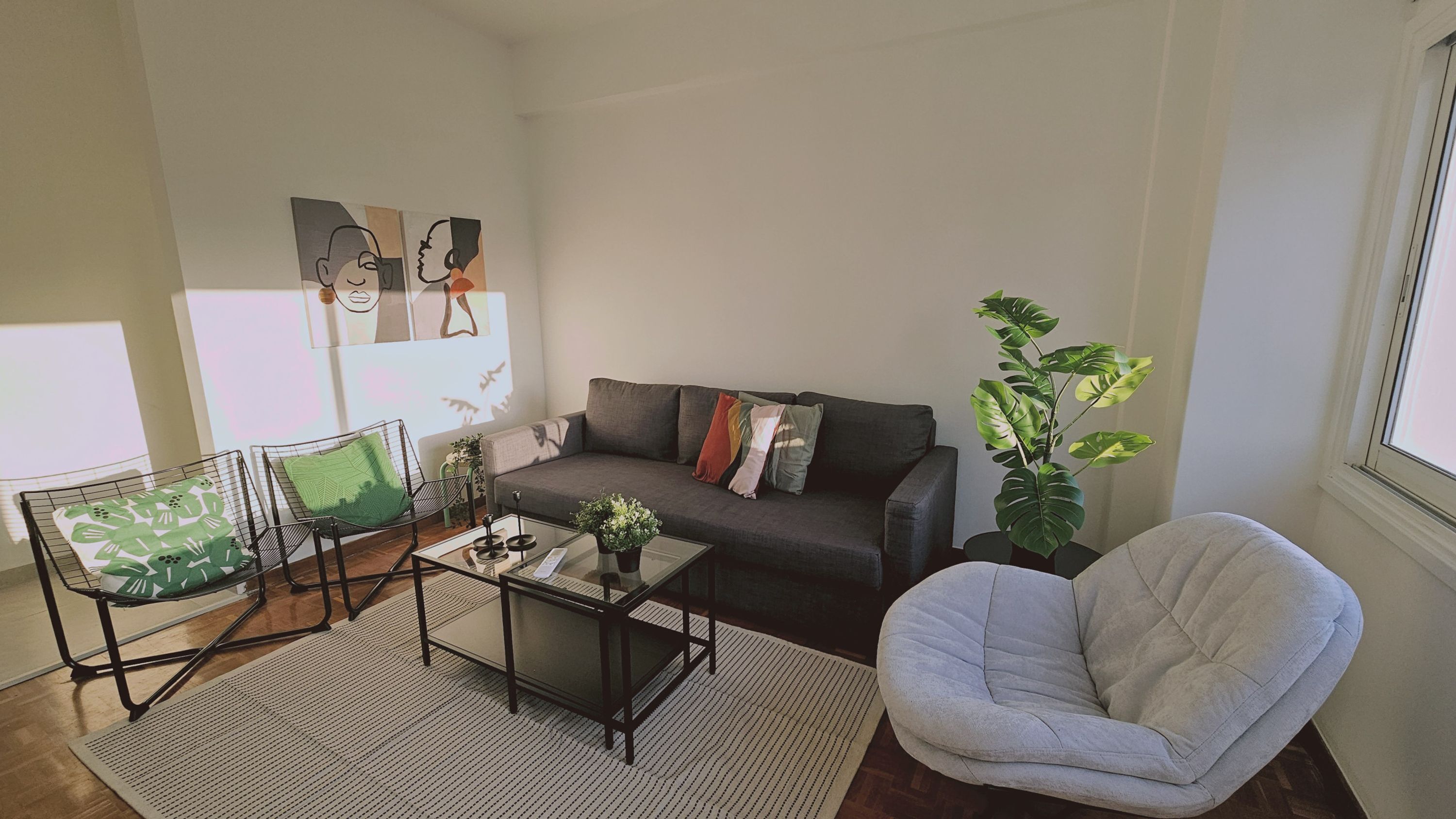 Ein Wohnzimmer mit einer Couch, zwei Sesseln, einem Couchtisch und einer Topfpflanze.
