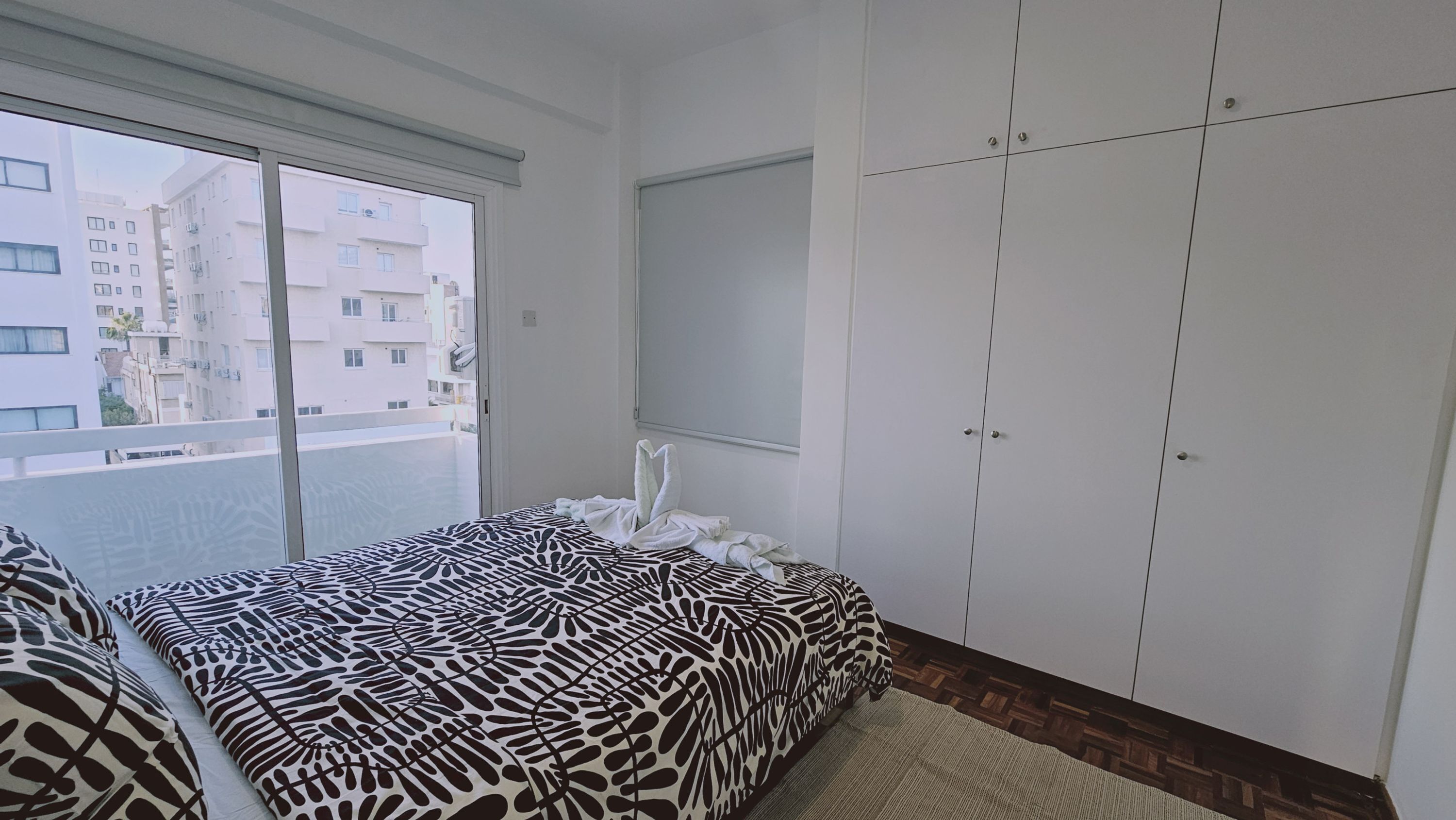 Een slaapkamer met een bed, een raam en een kledingkast.