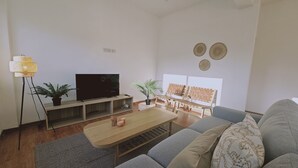 A modern living room with a flat-screen TV, wooden coffee table, grey sofa, and two potted plants. - 142 NIC 2 - Stay City Life 2 Apartment (Nicosia)