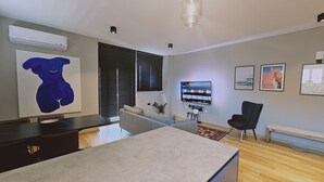Una sala de estar moderna con un sofá, una mesa de comedor y un televisor montado en la pared.