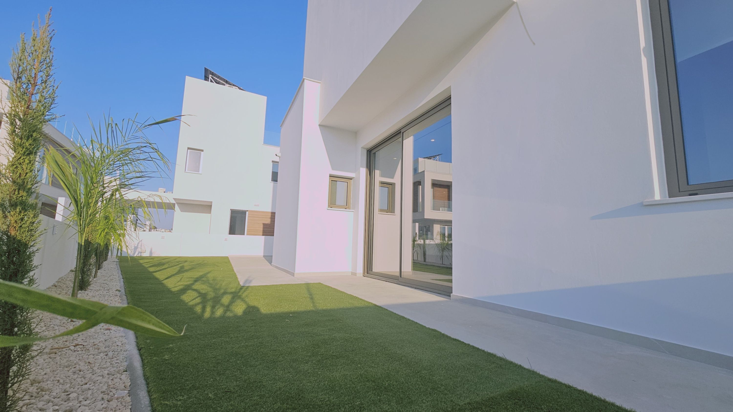 A modern building with a flat roof, large windows, and a paved pathway leading to a door.