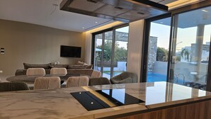 Un salon moderne doté d’un îlot en marbre, d’un ensemble de canapés et d’une grande fenêtre donnant sur une piscine.