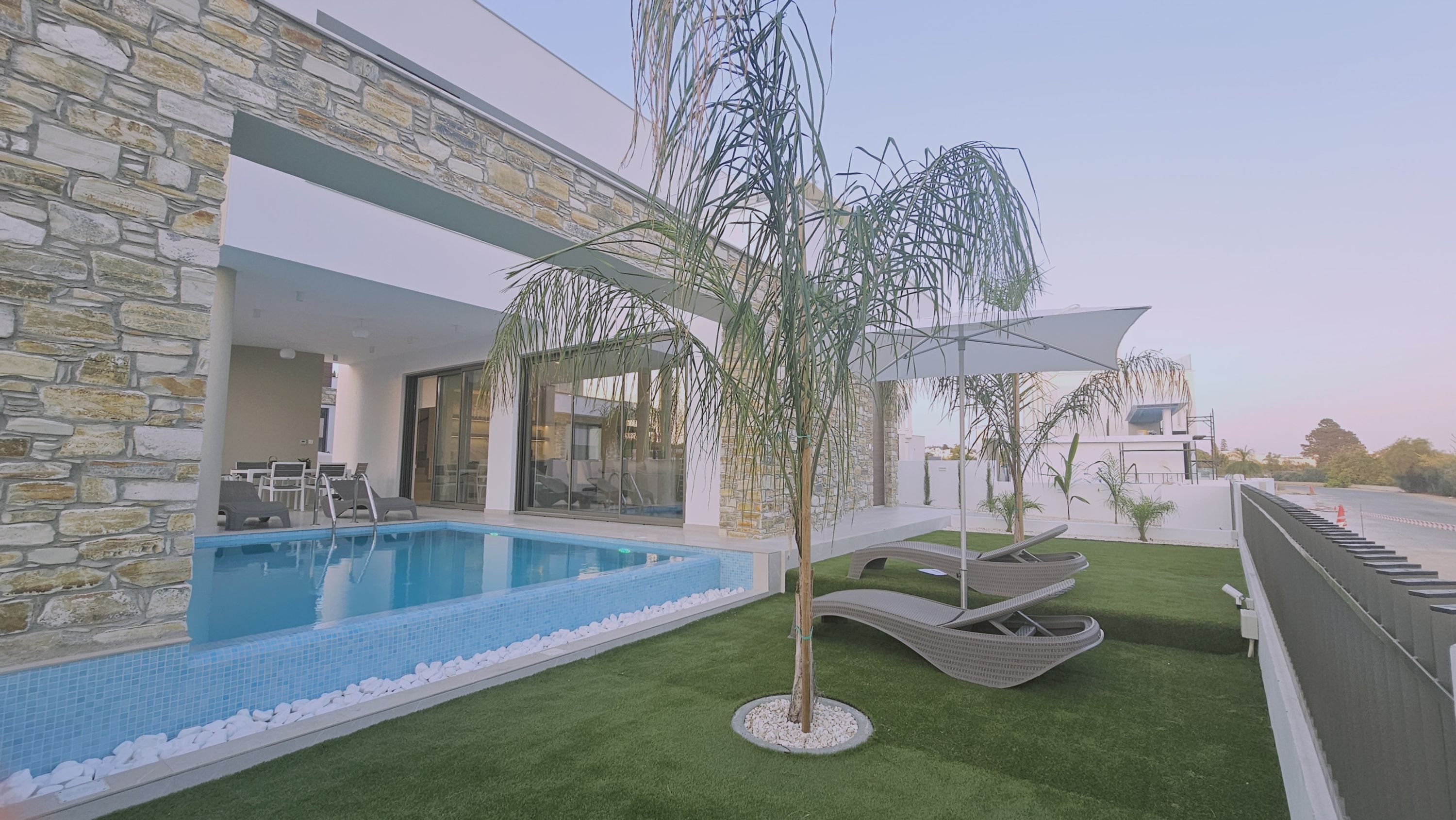 A modern house with a swimming pool, outdoor seating, and a stone facade.