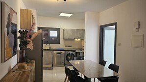 A compact kitchen with modern appliances, a dining area with a table and chairs, and a view of the living area.