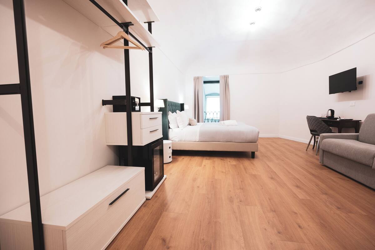 Ein modernes Hotelzimmer mit Bett, Schreibtisch, Fernseher und Blick ins Freie.