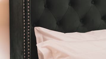 Una cama con cabecera tapizada en verde oscuro y almohada blanca.