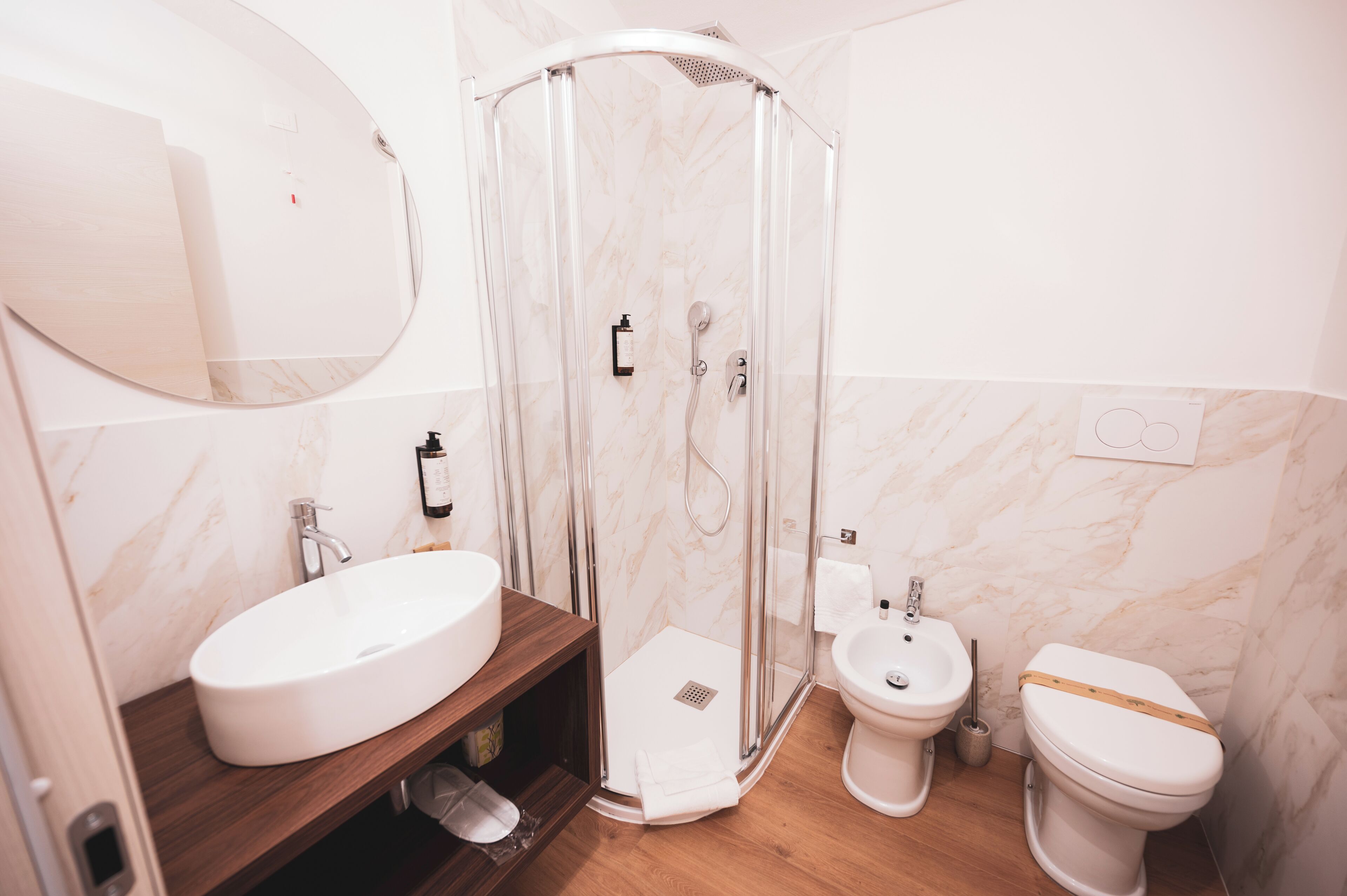 Een badkamer met douche, wastafel, toilet en toiletbril.