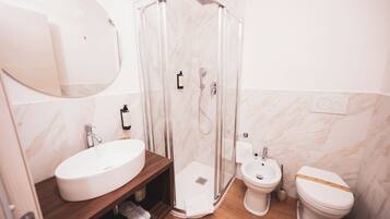 Een badkamer met douche, wastafel, toilet en toiletbril.