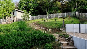 A garden with a wooden fence, a bench, and a bird sculpture.