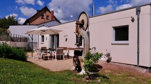 Una casa con un patio, mobiliario exterior y una gran maquinaria oxidada.