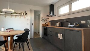 A modern kitchen with a wooden dining table, black chairs, and a built-in oven.