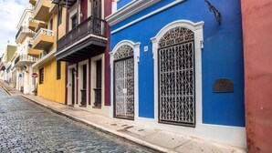 A cobblestone street lined with colorful buildings, each with distinct architectural styles and balconies.