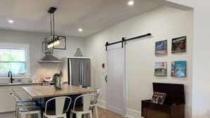 A modern kitchen with a wooden table and chairs, a stainless steel refrigerator, and a sliding door closet.