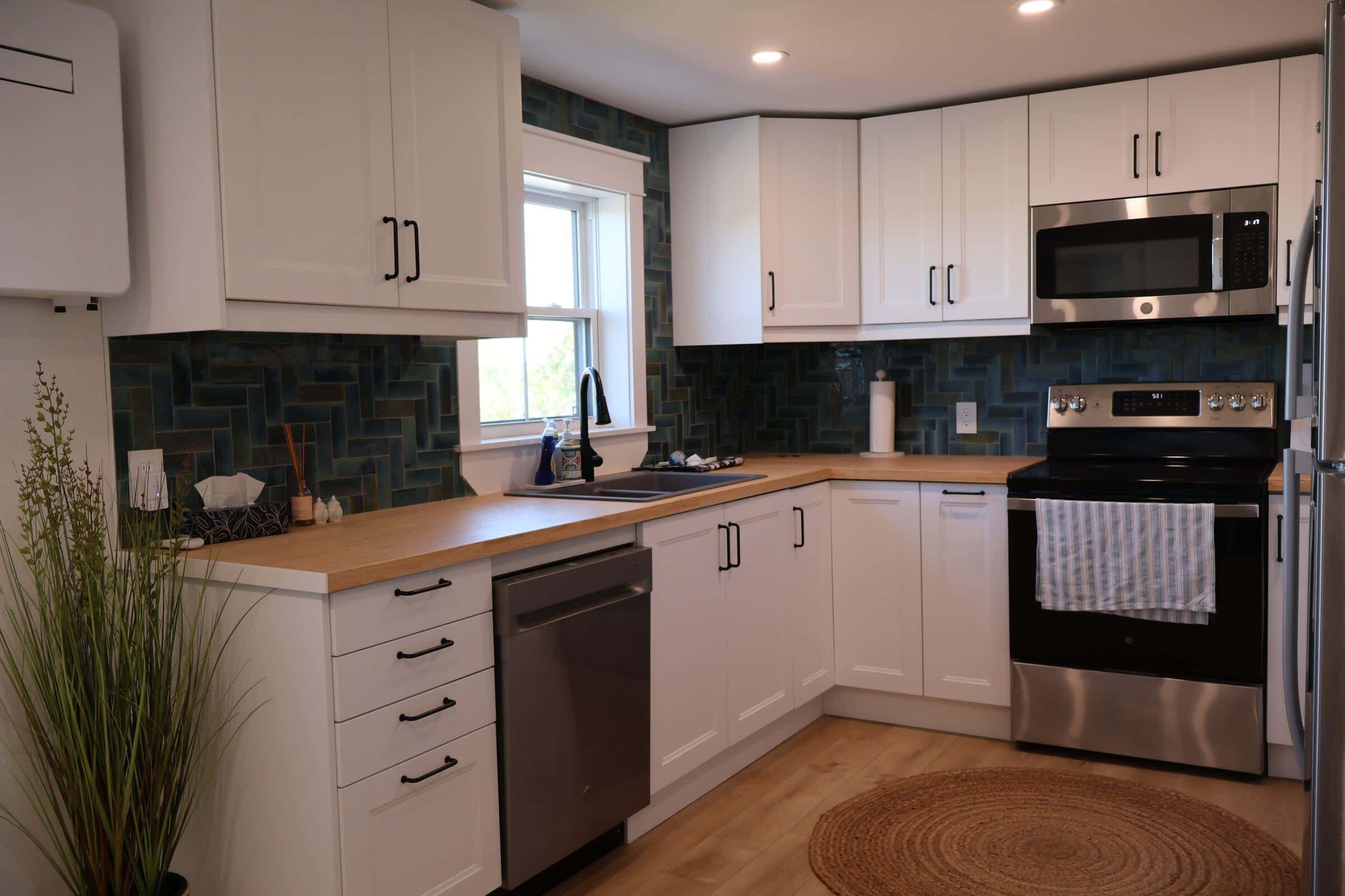 A modern kitchen with white cabinets, stainless steel appliances, a dishwasher, and a microwave.