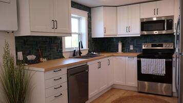 A modern kitchen with white cabinets, stainless steel appliances, a dishwasher, and a microwave.