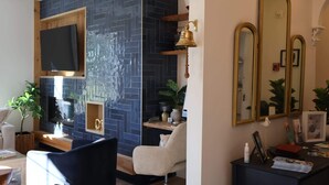 A modern interior with a TV mounted on a wooden panel, a desk with a computer, a chair, and a mirror.