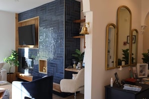 A modern room with a TV, a desk, a chair, and a large mirror.