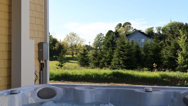 A hot tub with a view of a house and trees.