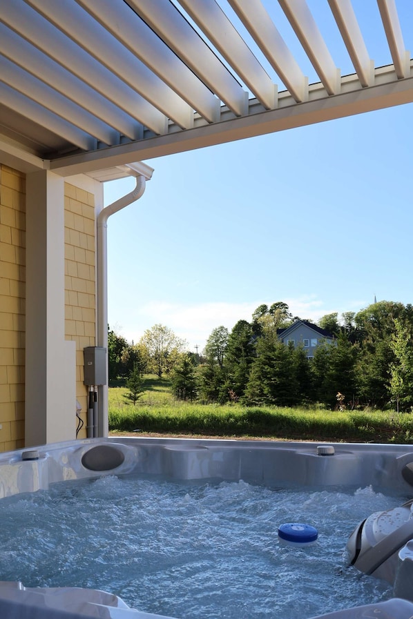 A hot tub with a view of a house and trees.