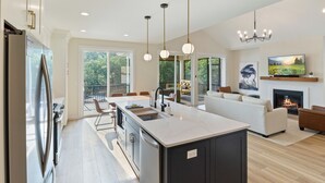 Una cocina moderna con una isla grande, un comedor con vistas y una sala de estar con chimenea.