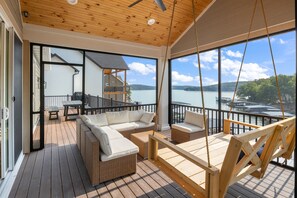 Une terrasse en bois avec des meubles en osier, une balançoire et une vue sur un lac.