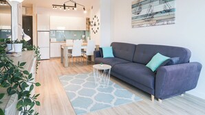 Un salon moderne comprenant un canapé, une table à manger et des chaises. Il y a également un coin cuisine avec des placards et un réfrigérateur.