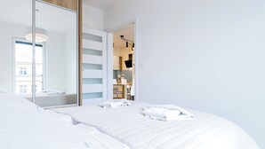 Une chambre d’hôtel avec un grand lit, un miroir et une vue sur la ville par la fenêtre.