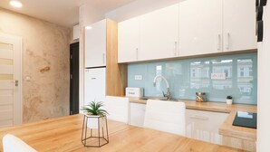 Une cuisine moderne avec des armoires blanches, un plan de travail en bois et un four encastré.