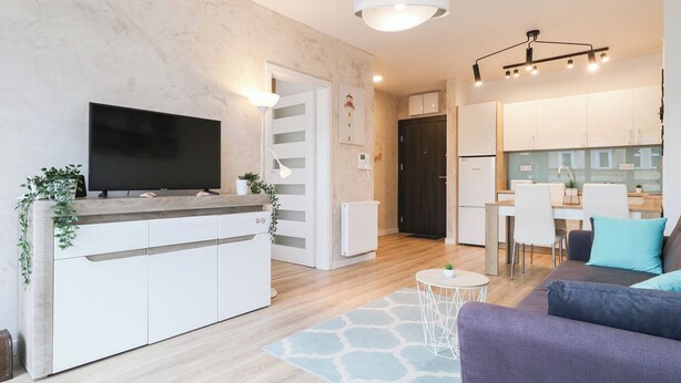 Un salon moderne avec un téléviseur, un canapé et un petit coin repas.