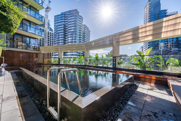 A rooftop swimming pool with a view of surrounding high-rise buildings.