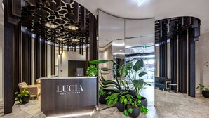 A modern reception area with a dark wood reception desk labeled "LUCIA SOUTH YAKRA".