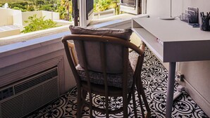 Habitación con vista al mar, un escritorio con silla y suelo estampado.
