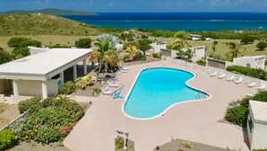 Un resort con piscina, sillones de descanso y vista al océano.