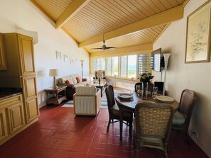 A spacious living area with a dining table, comfortable seating, and a view through large windows. - Beach & Golf retreat at The Reef awaits you! (Christiansted)