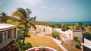 Un resort con varias construcciones, palmeras y vista al océano.
