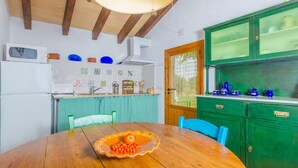 Una cocina con una mesa de madera, un microondas y armarios verdes.