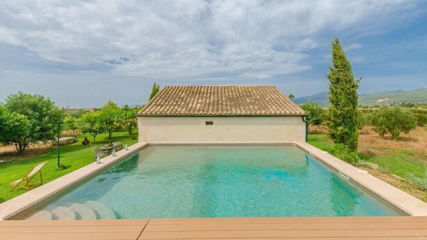 Una piscina con techo de azulejos, rodeada de vegetación y colinas.