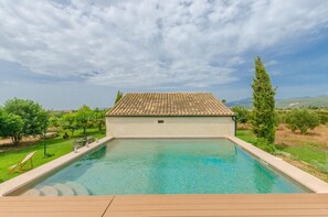 Une piscine dotée d’un toit carrelé, entourée de verdure et de collines.