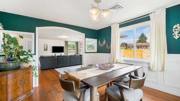 Una sala de estar moderna con comedor, televisor y vistas al exterior.