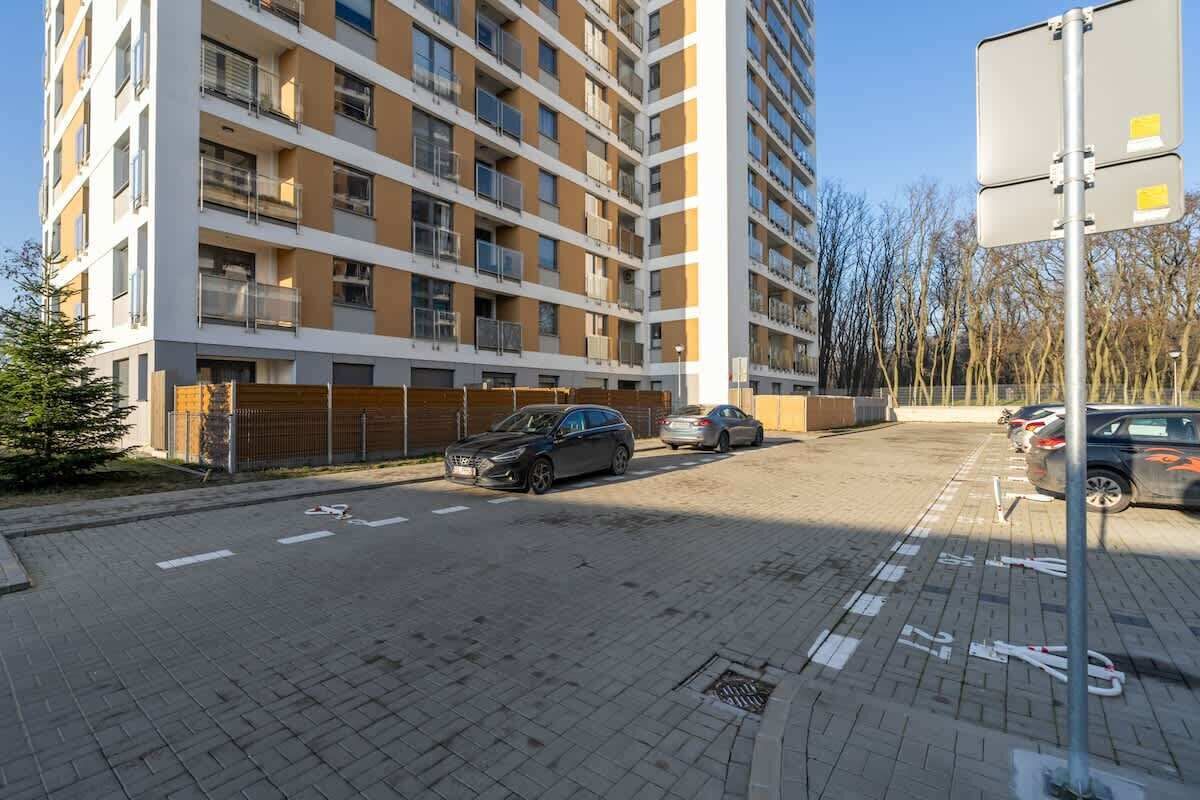 A multi-story residential building with a parking area in front.