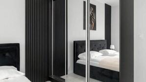 A modern bedroom with a large mirror, a dark headboard, and a bed with white linens.