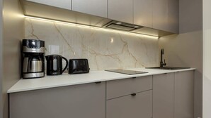 A modern kitchen with a marble backsplash, a coffee maker, a kettle, and a toaster.